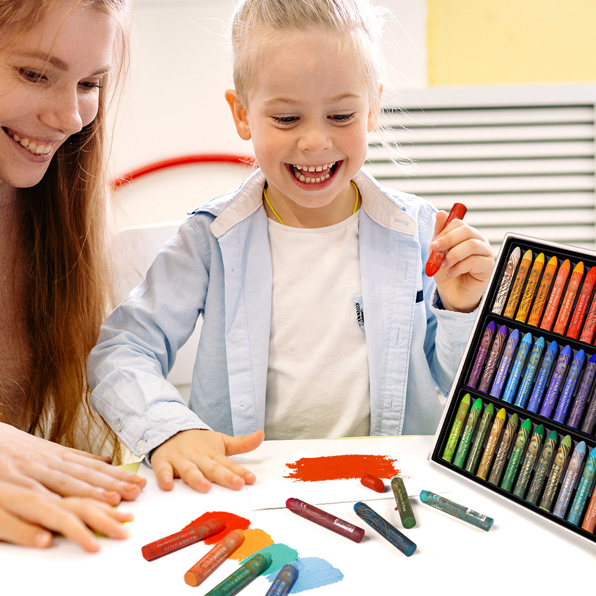 A woman and a child using crayons or oil pastels to make art on a table, surrounded by oil paint supplies.