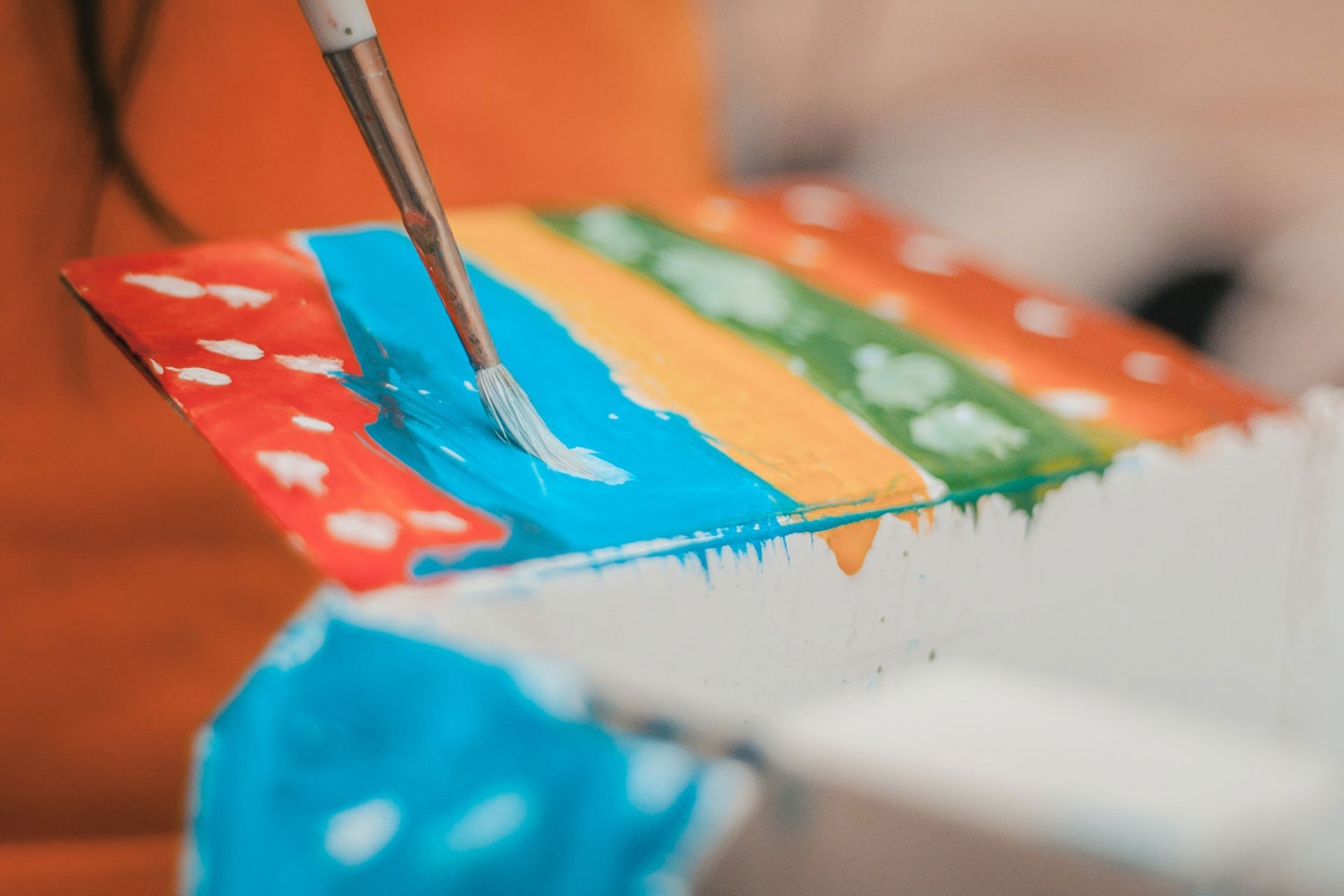 A board stained with colorful paint is dripping watercolor paint down